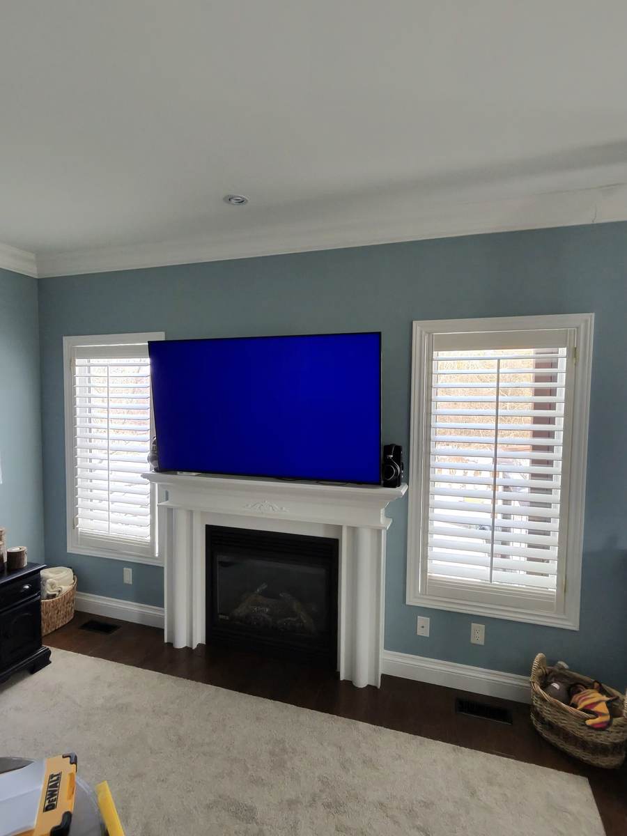 Above a fireplace mantel between two windows